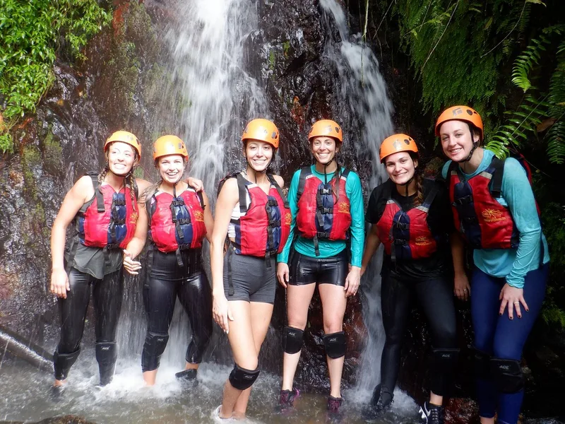 Small tour group wearing helmets and life jackets at an El Yunque waterfall